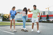 © blackday - Diverse carefree friends having fun and riding longboard on parking lot