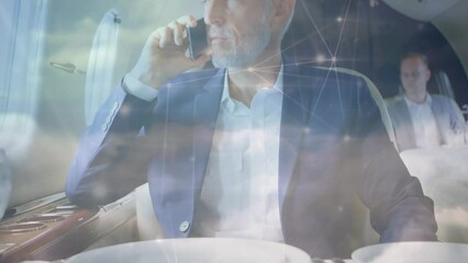 Canvas Print - Animation of connections and clouds over caucasian senior businessman using smartphone in plane