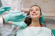 © Drobot Dean - White girl sitting in medical chair while dentists fixing her teeth