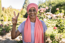 Happy Woman Gesturing Peace Sign In Public Park