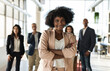 © Westend61 - Businesswoman with arms crossed standing with colleagues at office