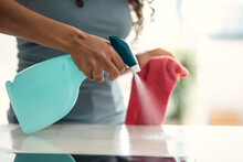 Hand Of Woman Cleaning Table At Home Spraying Water