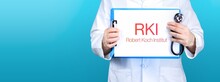 RKI (Robert Koch-Institut). Arzt Hält Blaues Schild Mit Papier. Wort Steht Auf Dokument. Stethoskop In Der Hand.