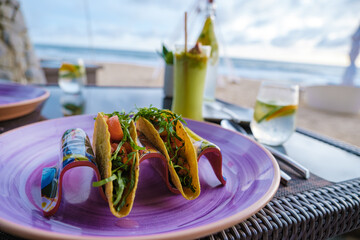 tacos in a yellow corn tortilla with avocado, onion, cilantro, and cabbage, Dinner during sunset on the beach in Phuket Thailand Khao Lak