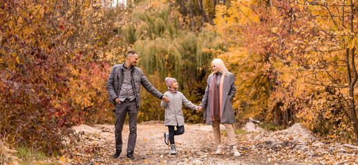 Wall Mural - A Family of four enjoying golden leaves in autumn park