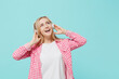© ViDi Studio - Young happy smiling european woman she 30s wear pink shirt white t-shirt headphones listen to music look aside isolated on plain pastel light blue background studio portrait. People lifestyle concept.