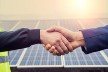 Workers In Work Clothes Greet Each Other By The Hand Before Starting Work On Solar Panels.