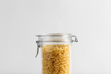 food storage, eating and cooking concept - close up of jar with pasta on white background