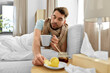 © Syda Productions - health, illness and people concept - sick man drinking hot tea with lemon and honey in bed at home