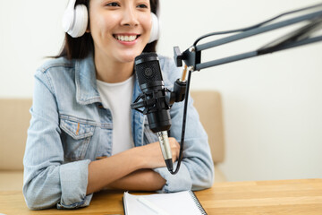 Wall Mural - Content creator woman host streaming her a podcast on laptop with headphones and microphone interview cheering guest conversation at broadcast studio. Blogger motivation recording voice over radio.