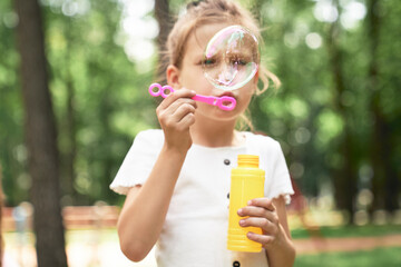 Wall Mural - Caucasian girl blowing soap bubbles at the park