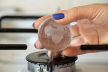 A Woman's Hand Holds A Small Ball Of Earth Over A Gas Burner At Home, A Global Gas Problem, Gas Refusal