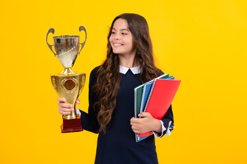 schoolgirl in school uniform celebrating victory with trophy. teen holding winning award prize on ye