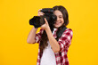 © Olena - 12, 13, 14 year old teen girl holding digital camera or DSLR over yellow background. Happy teenager, positive and smiling emotions of teen girl.