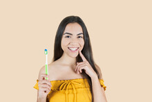 Oral Hygiene And Teeth Care Concept. A Positive Young Hispanic Woman With Long Hair, Is Holding A Toothbrush, Cleaning Her Teeth, Has Brown Skin, And Is In A Great Mood. Health And Dentistry