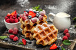 © Надія Коваль - Belgian waffles with raspberries, strawberries and blueberries, sugar powder over black background