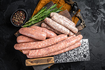 Mix fresh raw sausages. Beef, pork, lamb and chicken mince meat sausages on a butcher cutting board with spices. Black background. Top view