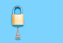 Padlock And Key On A Blue Background With Space For Text. Golden Lock And Key That Opens And Closes It. The Concept Of Protection And Reliability. Free Space For Ads And Text