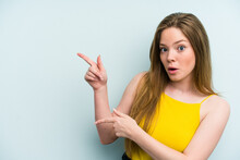 Young Caucasian Woman Isolated On Blue Background Pointing With Forefingers To A Copy Space, Expressing Excitement And Desire.