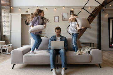 Caucasian male working from home with children. Work From Home Stressed Parent. Noisy active daughters playing at home