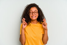 Young Brazilian Woman Isolated On Blue Background Crossing Fingers For Having Luck