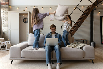 Wall Mural - Caucasian male working from home with children. Work From Home Stressed Parent. Noisy active daughters playing at home