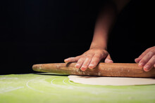Rolling Out Dough With Hands On A Dark Background