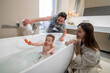 © zinkevych - Smiling parents looking at baby playing in bathtub