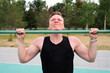 © Евгений Шемякин - handsome man, young fitness strong athletic guy pulls himself up on the horizontal bar outdoors at gym open air at summer day. Bodybuilding, healthy lifestyle concept.