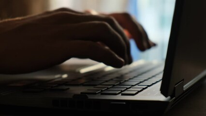 Male hands typing text on a laptop keyboard, close-up