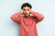 © Asier - Young caucasian man isolated on blue background covering ears with hands trying not to hear too loud sound.