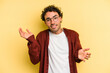 © Asier - Young caucasian man isolated on yellow background confused and doubtful shrugging shoulders to hold a copy space.