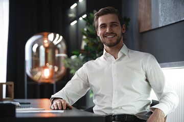 Portrait of businessman sitting in office, successful man worker employee by work desk looking at camera