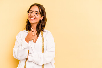 Wall Mural - Young nutritionist hispanic woman isolated on yellow background smiling and raising thumb up