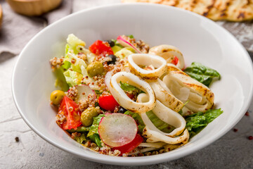 Wall Mural - salad with squid and vegetables on white plate on white wooden table