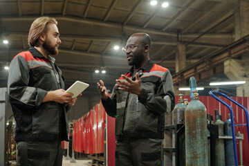 Aufkleber - Young serious male engineer looking at his African American colleague describing characteristics of new industrial equipment