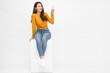 © comzeal - Young Asian woman sitting and pointing to empty copy space isolated on white background, Full body composition