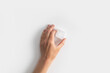 Woman's hand holding an ice cube on a white background. Top view, flat lay