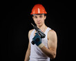 © justoomm - a young construction worker is a teenager in a hard hat and a white T-shirt with a screwdriver in his hand.