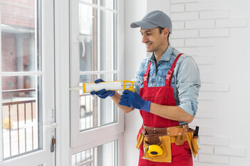 Wall Mural - Construction worker installing window in house. Handyman fixing the window with screwdriver