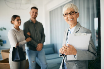 Portrait of happy senior financial advisor with her clients in background.