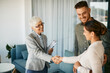 © Drazen - Happy senior financial advisor shaking hands with young couple after successful meeting in the office.