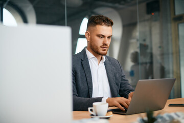 Wall Mural - Young male entrepreneur using laptop while working in office.