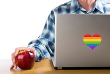 Person Works On Computer That Has A Heart With The Colors Of The LGBTQ Movement. Concept Of Tolerance, Inclusion And Diversity