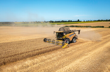 Aufkleber - Combine harvester on a wheat field with blue sky.