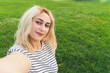 © PoppyPix - selfie of a young blond girl at the park. medium closeup outdoor copy space. High quality photo