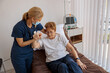 © Yaroslav Astakhov - Female nurse in mask helping patient to get up from bed in the ward at hospital. High quality photo