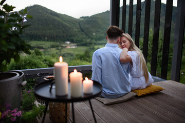 Wall Mural - Young couple resting outdoors on terrace of tiny house in woods with view in evening, weekend away in tiny house in countryside, sustainable living.