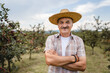 © Miljan Živković - One man front view portrait of senior male farmer standing in the cherry orchard in summer day confident pensioner looking to the camera on his plantation wearing straw hat copy space