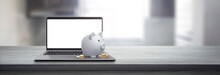Piggy Bank With Coins On A Wooden Table Next To A Laptop - Savings Concept